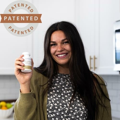 Woman smiling and holding a supplement bottle in a kitchen.